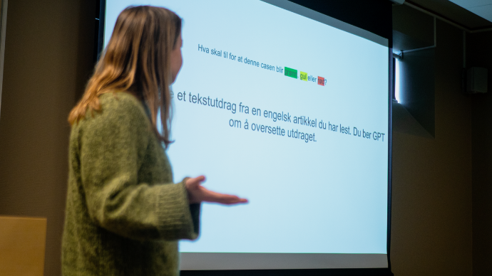 Person som står foran studenter og leser opp en problemstilling